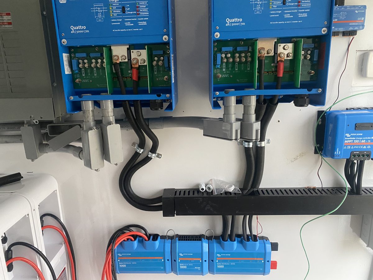 Close-up of two off-grid inverters with conduit and DC distribution