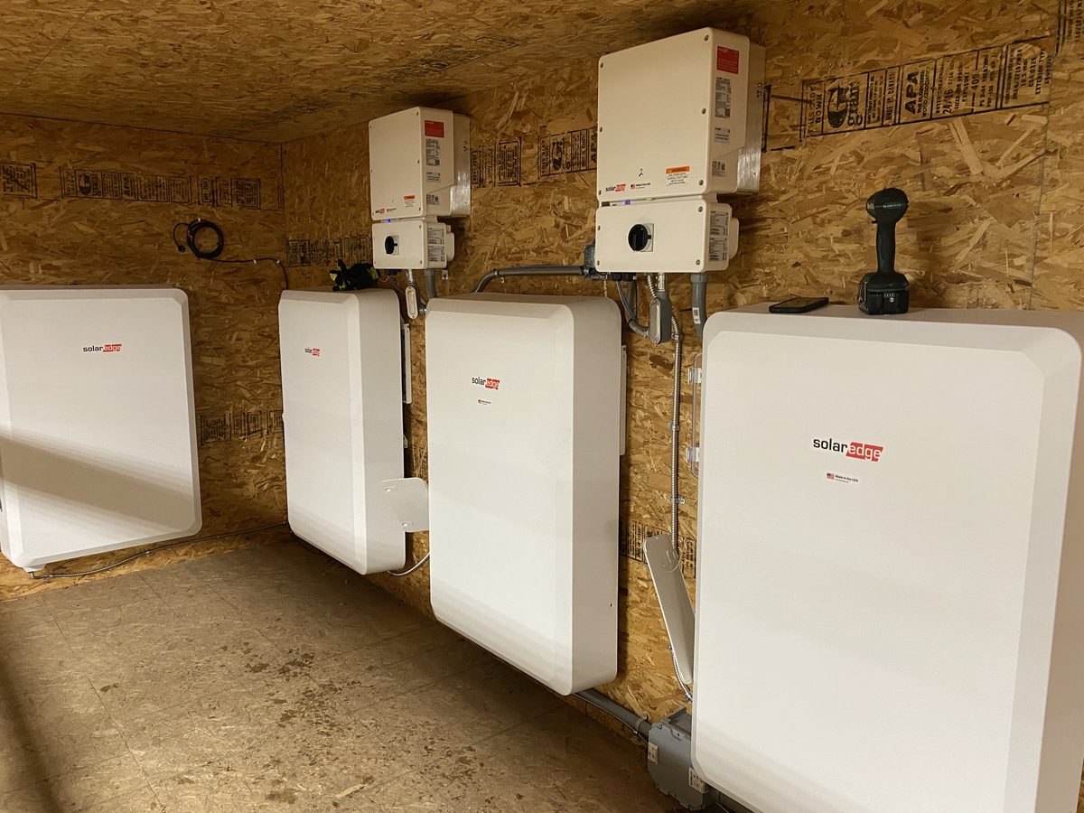 Row of SolarEdge batteries and inverters mounted in a mechanical room