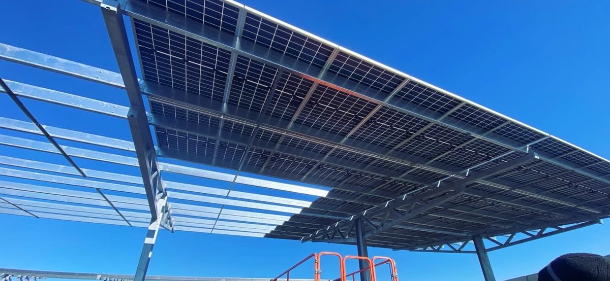 Solar carport canopy seen from below against a clear blue sky