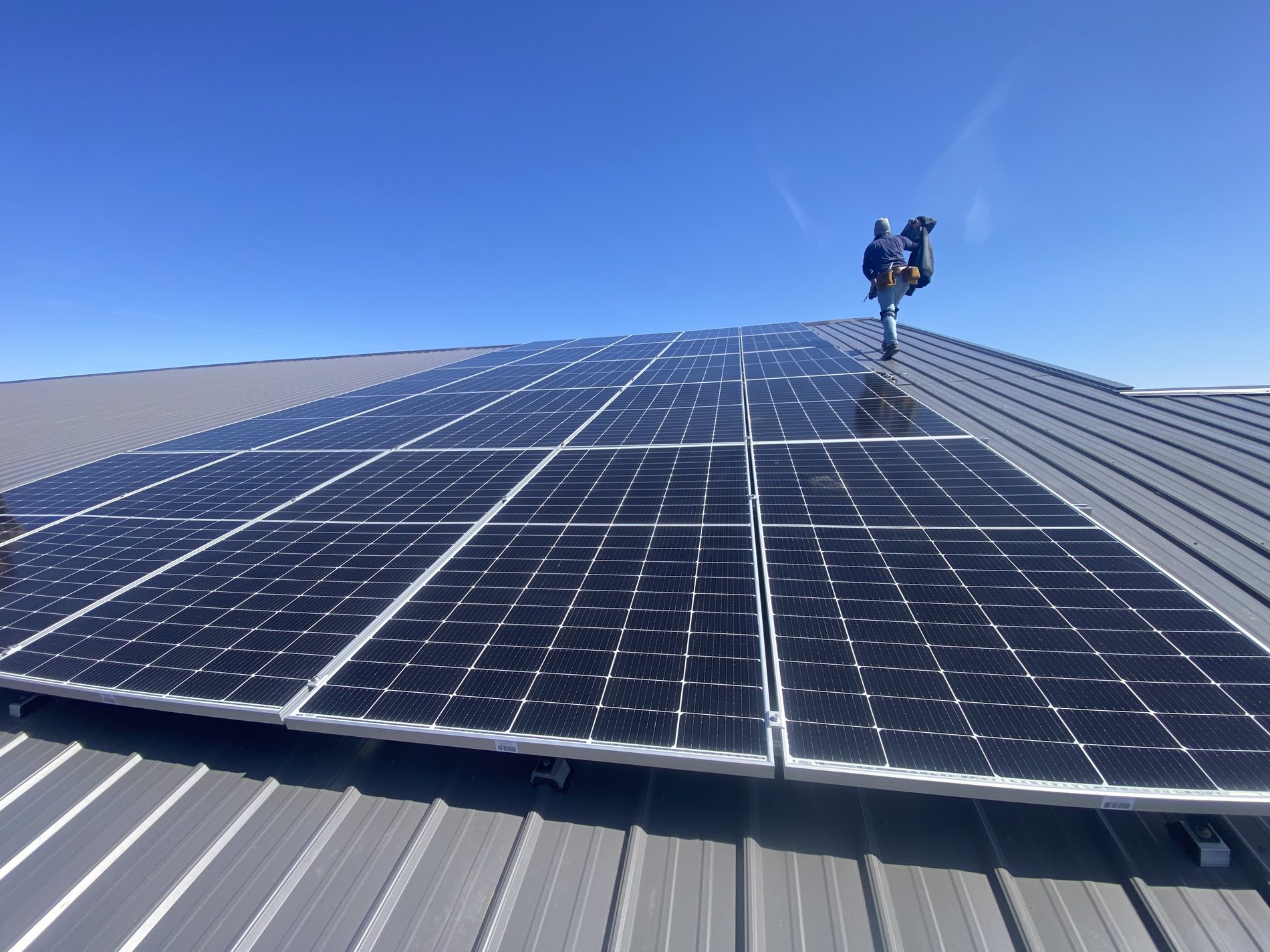 Solar installer setting modules on a standing seam metal roof in northern Indiana