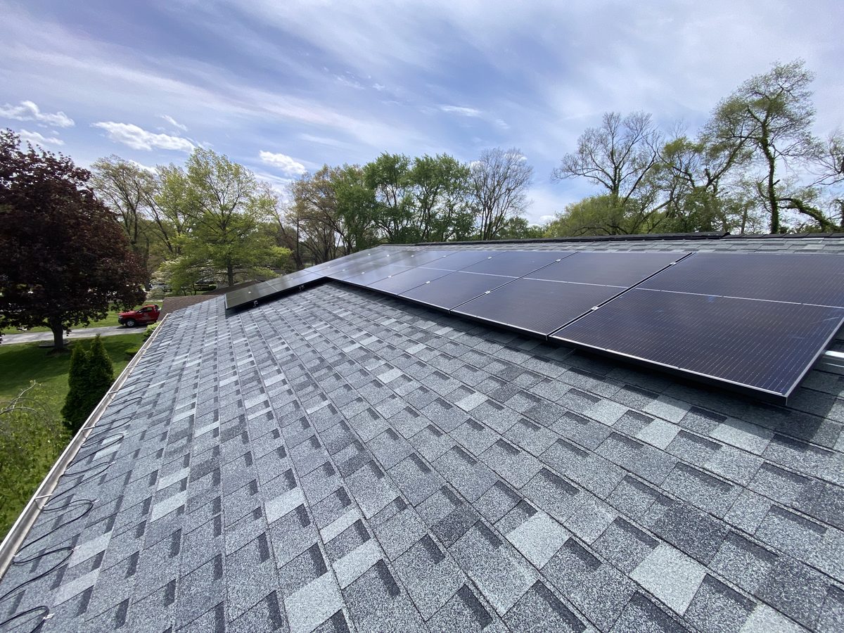 Solar modules flush-mounted on a gray shingle roof under a blue sky