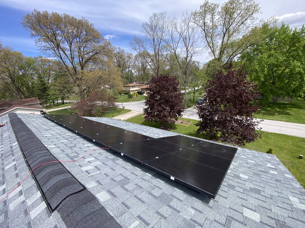 All-black solar modules running along a shingle roof ridge