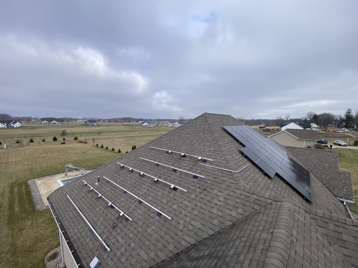 Mounting rails and wiring laid out on a shingle roof before panels go on